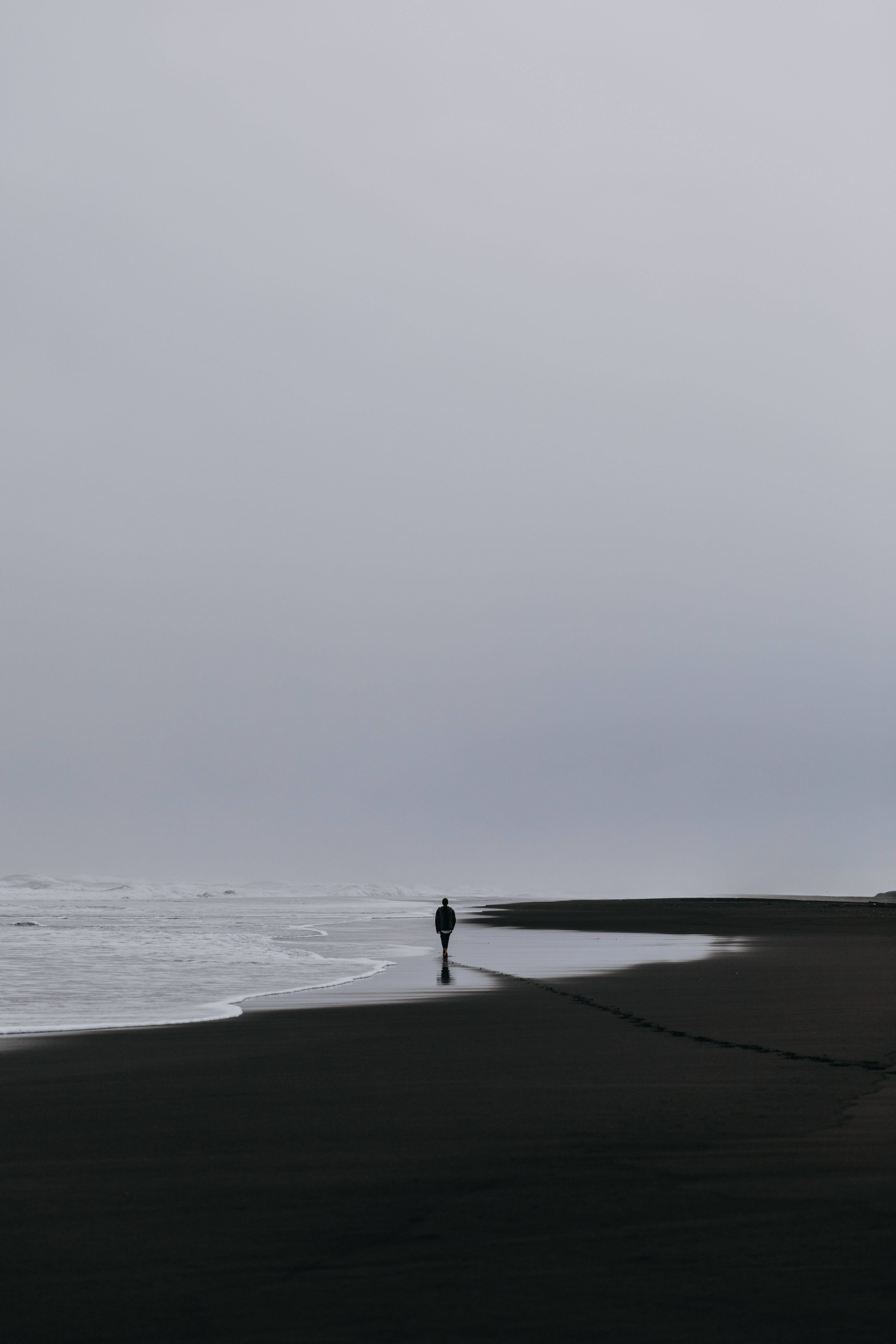 A Man Walking Alone On The Beach With His Phone Wallpaper