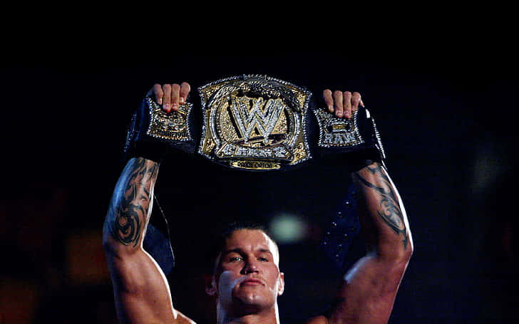 A Wrestler Holding Up A Wwe Championship Belt Wallpaper