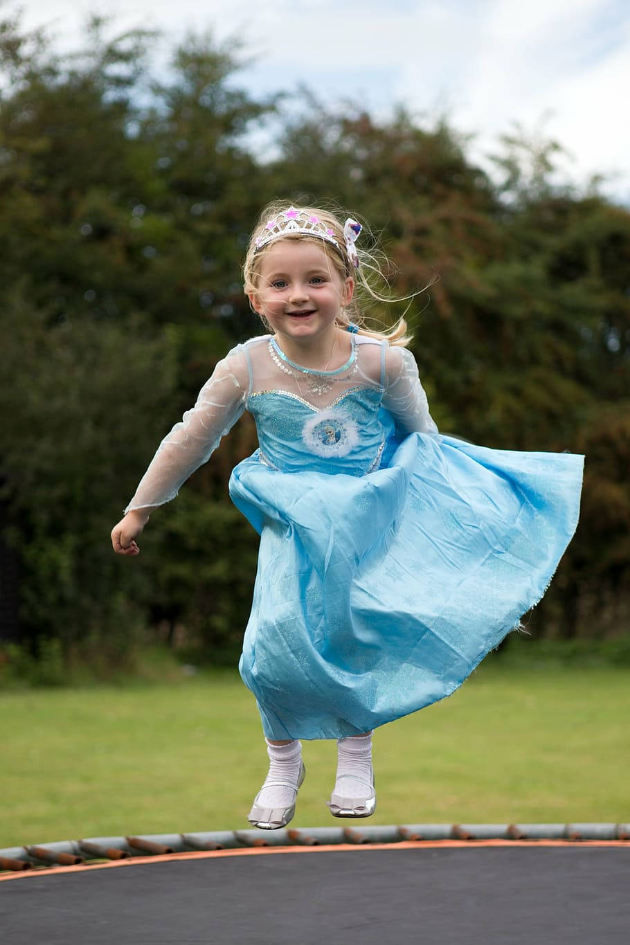 Adorable Girl In Gown Jumping On Trampoline Wallpaper