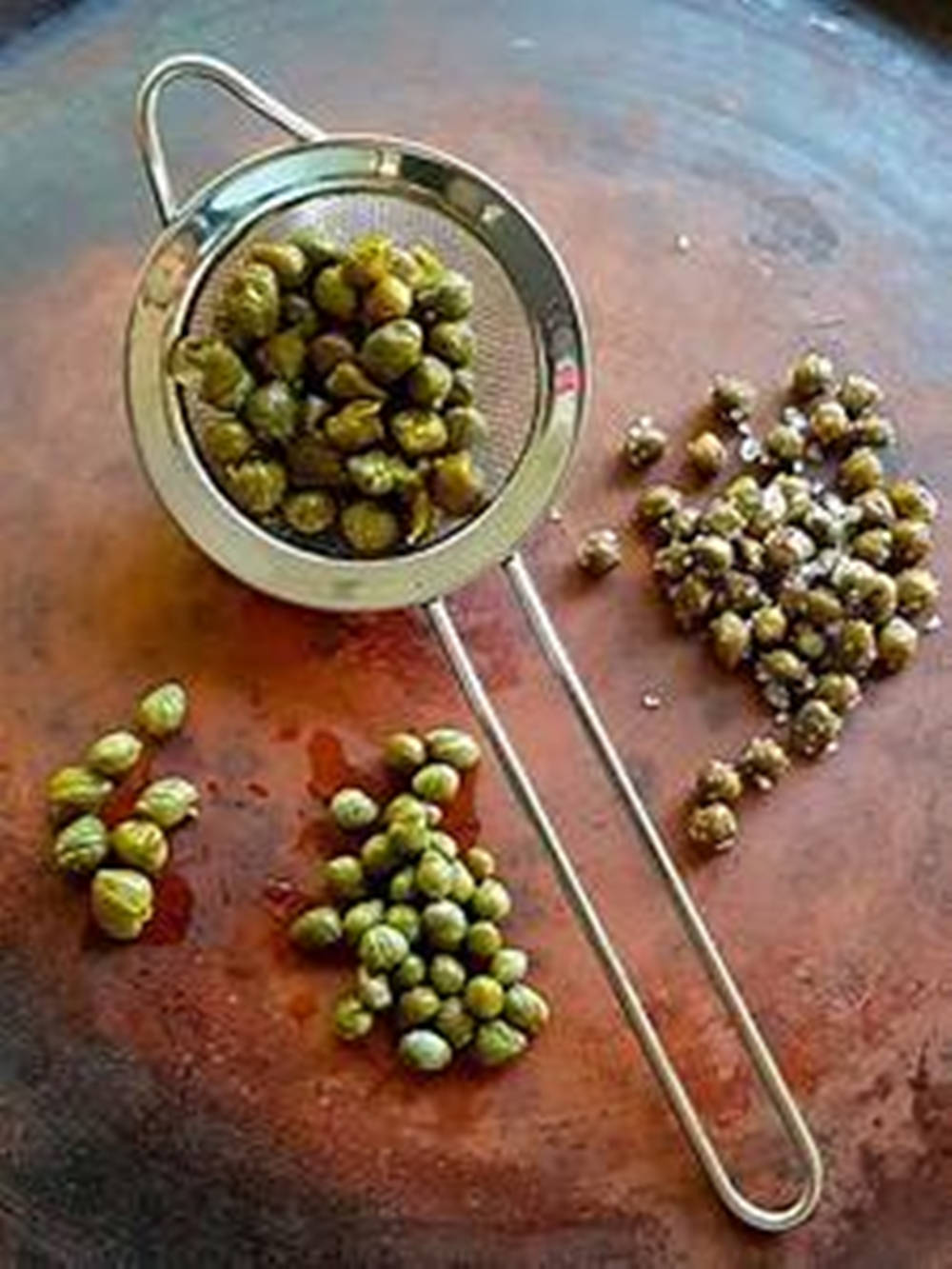 Capers In Mini Strainer On Wood Board Wallpaper