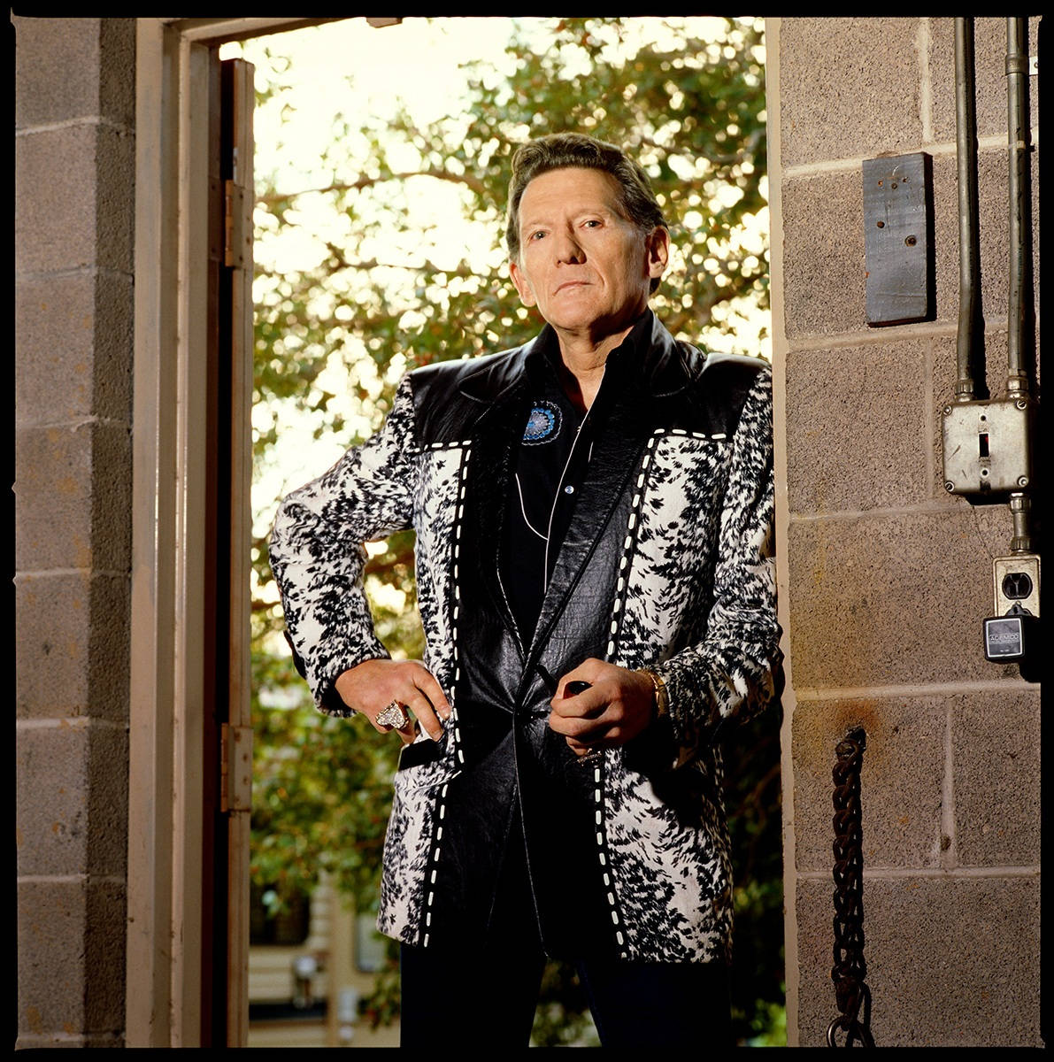 Caption: Legendary Rock 'n' Roll Pioneer, Jerry Lee Lewis Leaning On A Doorway Wallpaper