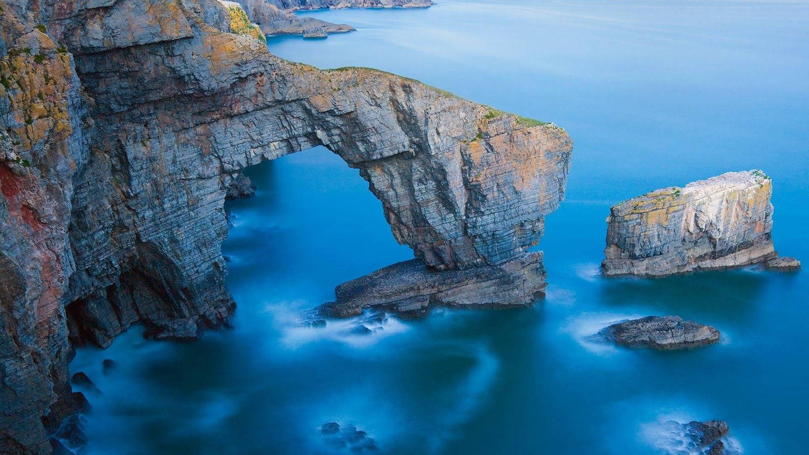 Driftwood And Pebbles On A Stunning Beach In The Pembrokeshire Coast National Park Wallpaper