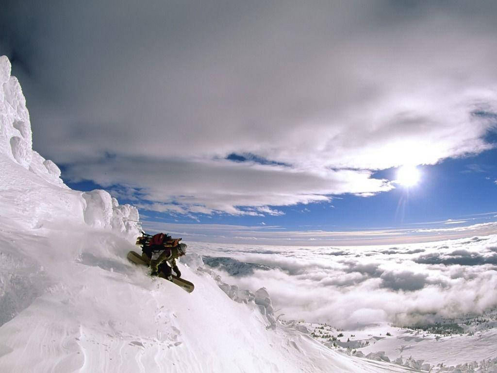 Man With Snowboard Dashes Down A Mountain Wallpaper