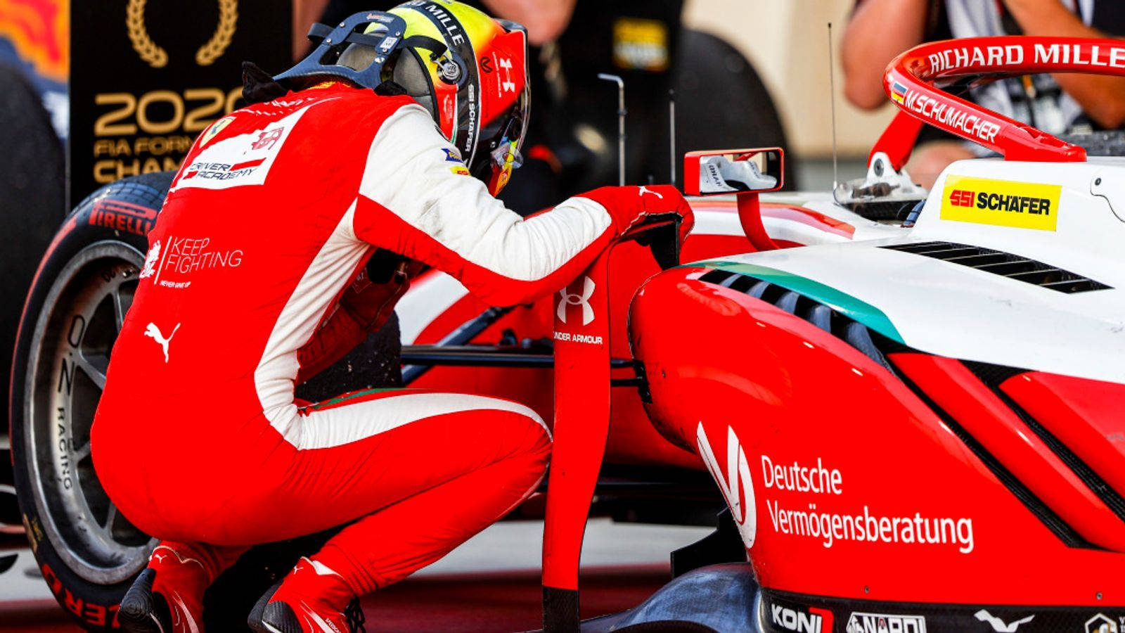 Mick Schumacher Crouched Over A Car Wallpaper