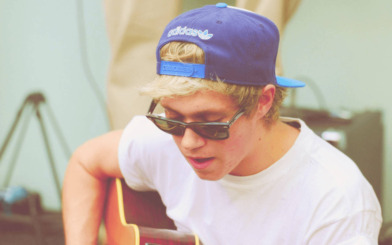 Niall Horan Cap Playing Guitar Wallpaper