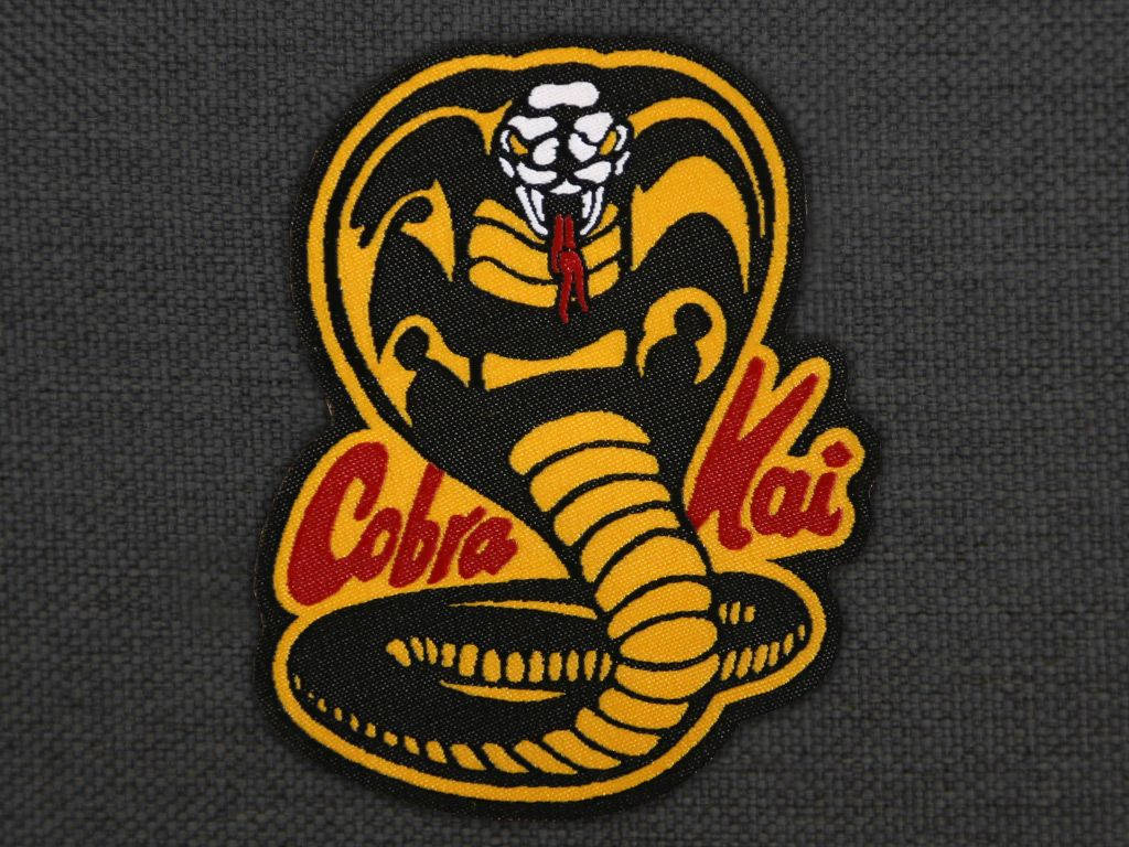 Own Your Legacy With The Official Cobra Kai Logo Patchwork. Wallpaper