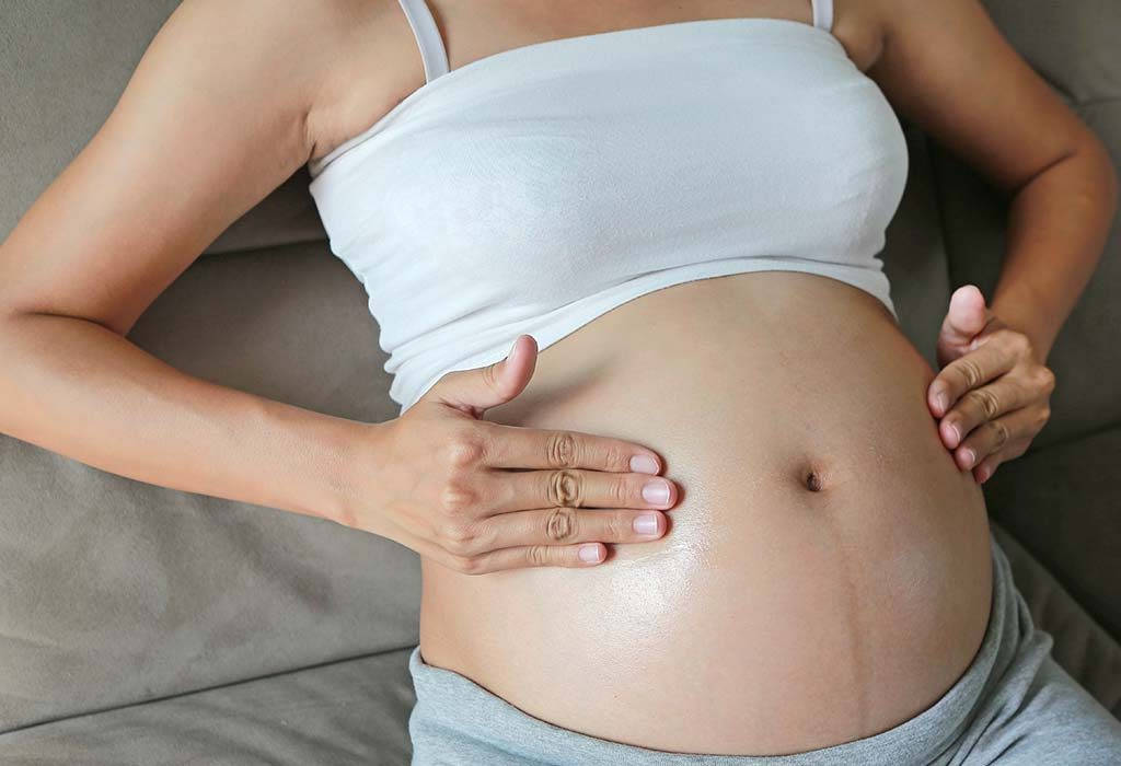 Serene Mother-to-be Cradling Her Growing Belly Wallpaper