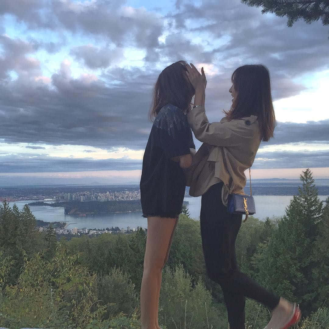 Two Women Standing On A Hill Overlooking The City Wallpaper