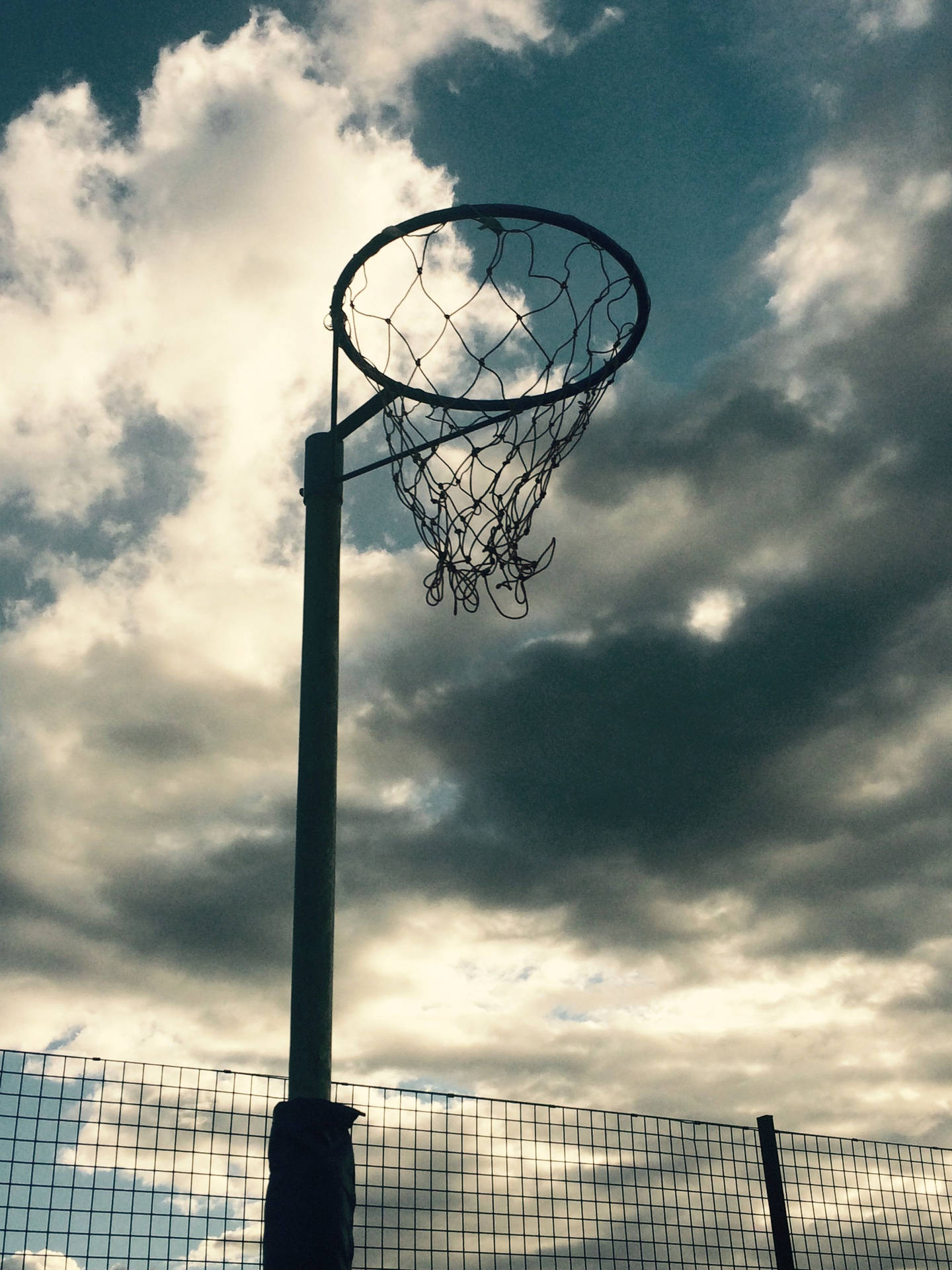 Victory At Her Fingertips – A Netball Player Aiming For The Hoop On An Outdoor Court Wallpaper