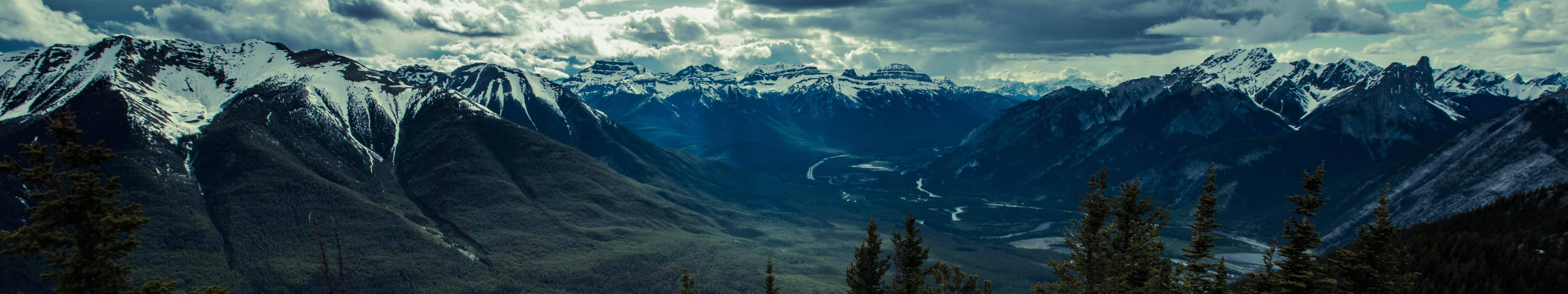 View Of The Mountains With A Triple Monitor Setup Wallpaper