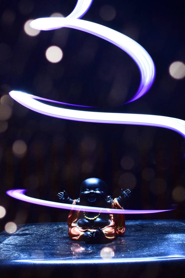 A Baby Buddha Figurine, Representing Enlightenment And Wisdom Wallpaper