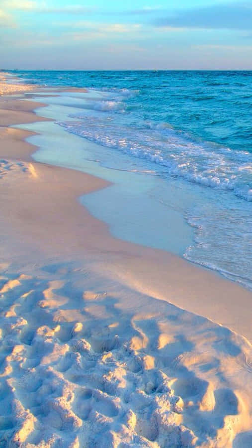 A Beach With White Sand And Blue Water Wallpaper
