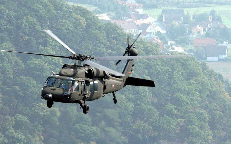 A Black Helicopter Flying Over A Forest Wallpaper