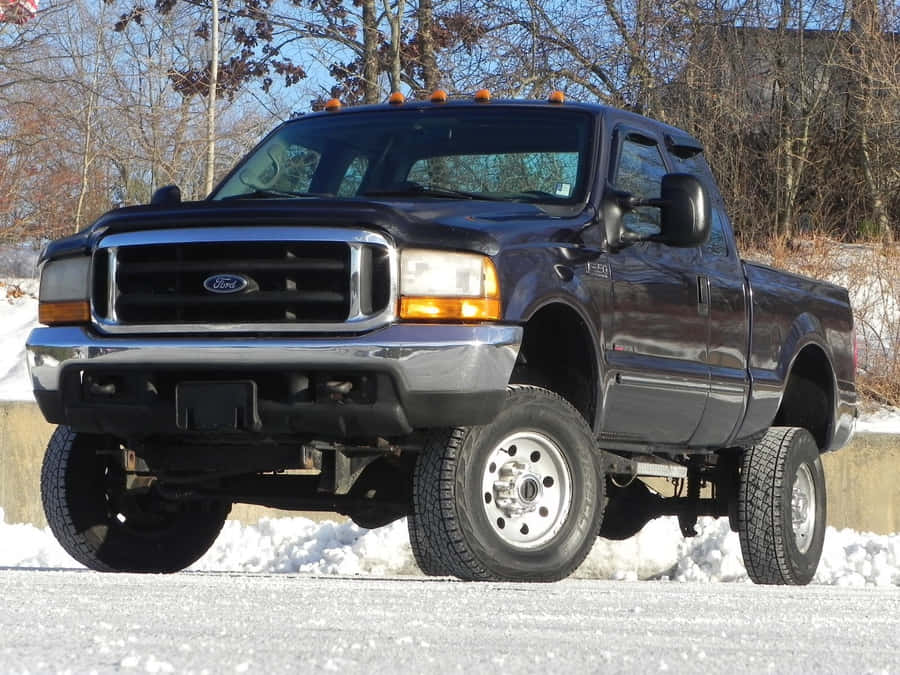 A Black Truck Is Parked In The Snow Wallpaper