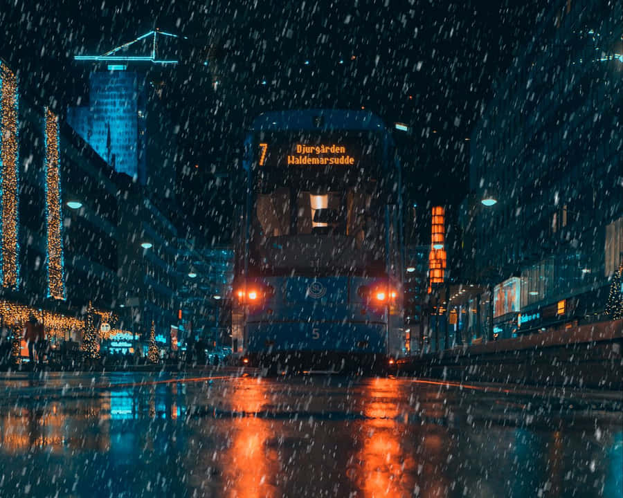 A Blue Tram Driving Down A City Street At Night Wallpaper