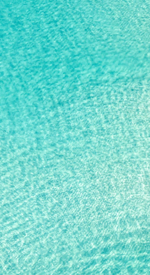 A Blue Water Surface With A White Sand Beach Wallpaper