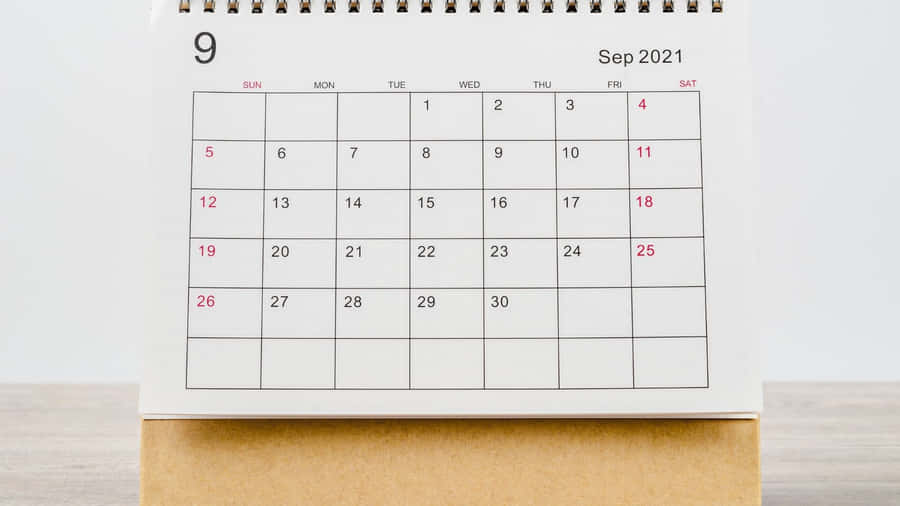 A Calendar With A White Background On A Wooden Table Wallpaper