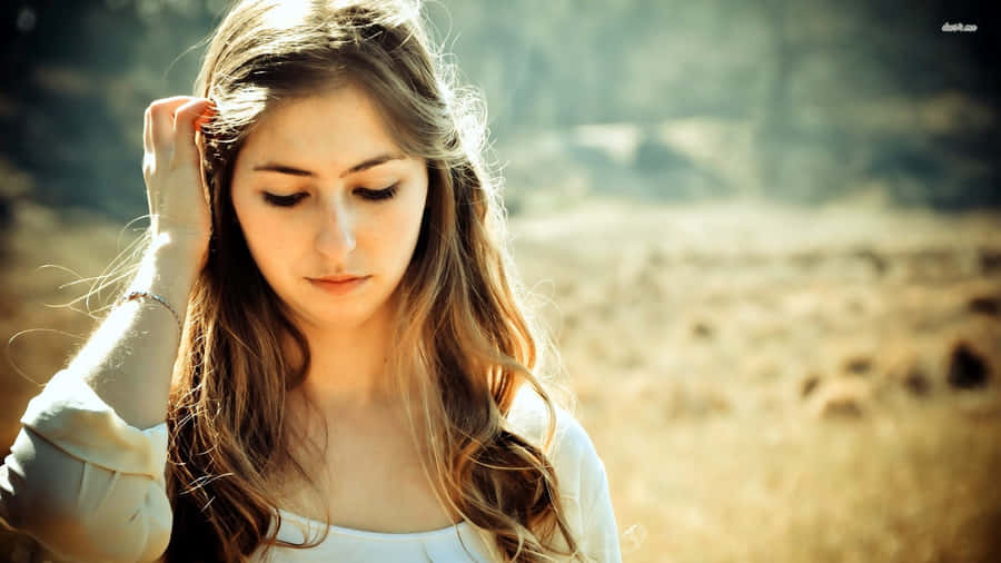 A Girl With Her Head Down In A Field Wallpaper