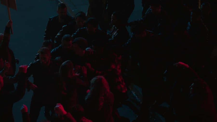 A Group Of People Are Standing In A Street At Night Wallpaper