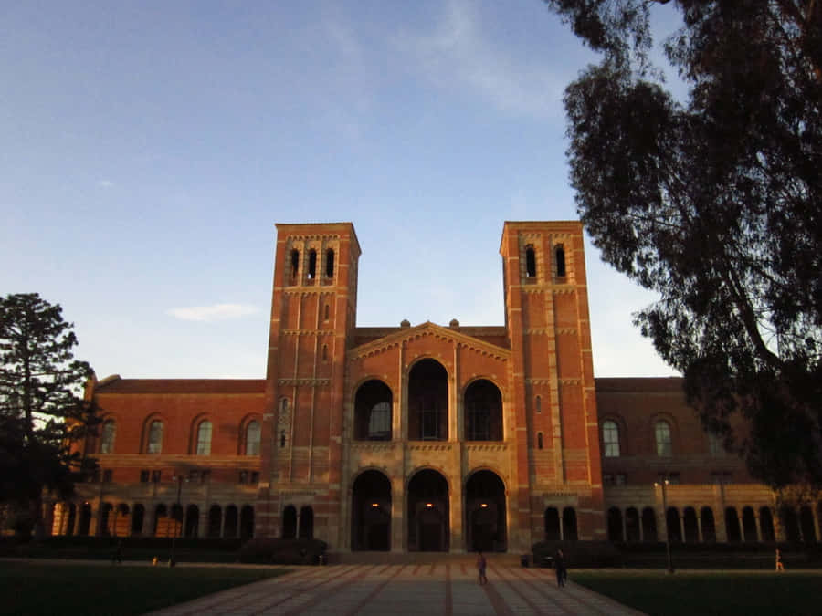 A Large Brick Building With Trees And A Clock Tower Wallpaper