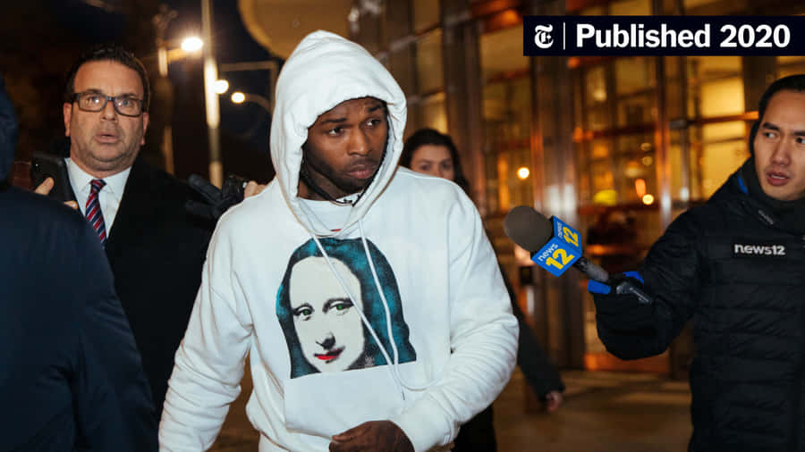 A Man In A Hoodie Is Walking Down The Street Wallpaper