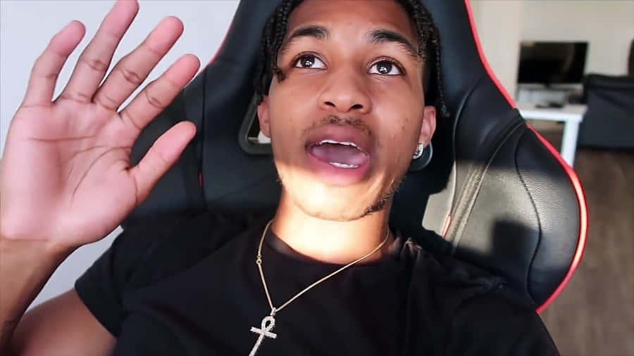 A Man Is Sitting In A Chair And Making A Gesture Wallpaper