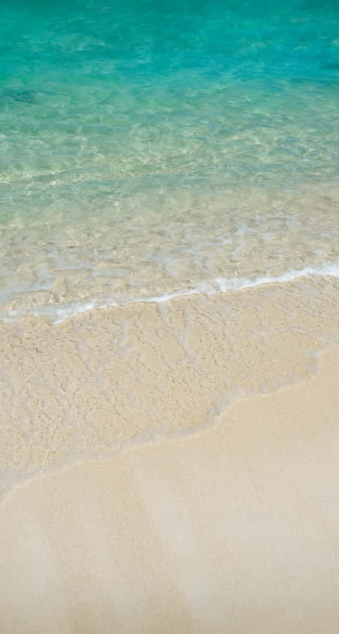 A Man Is Walking On A Sandy Beach With Water Wallpaper