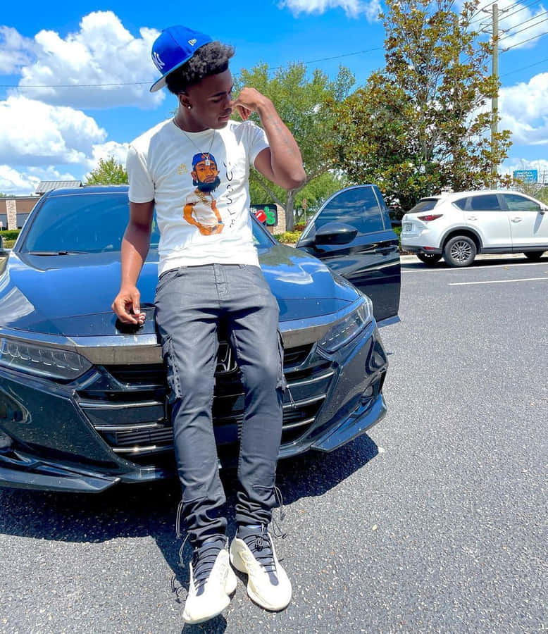 A Man Sitting On The Side Of A Black Car Wallpaper