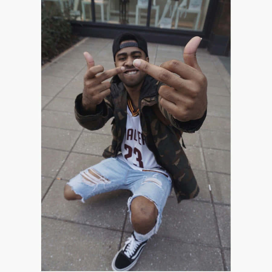 A Man With A Hat And Jeans Is Giving The Thumbs Up Wallpaper