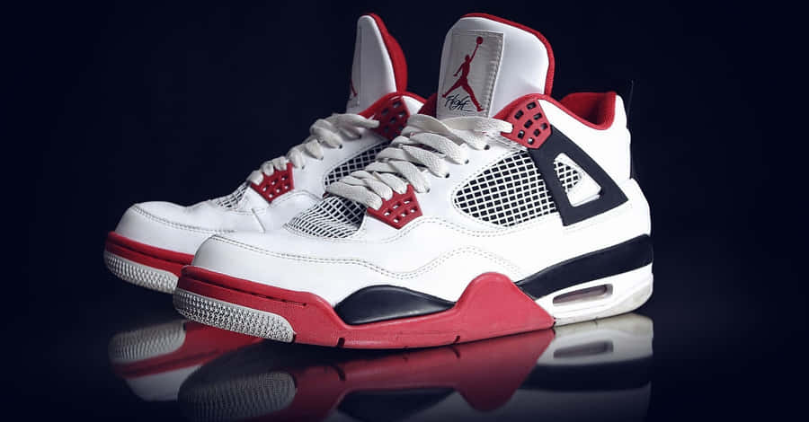 A Pair Of White And Red Air Jordan 4 Sneakers Wallpaper