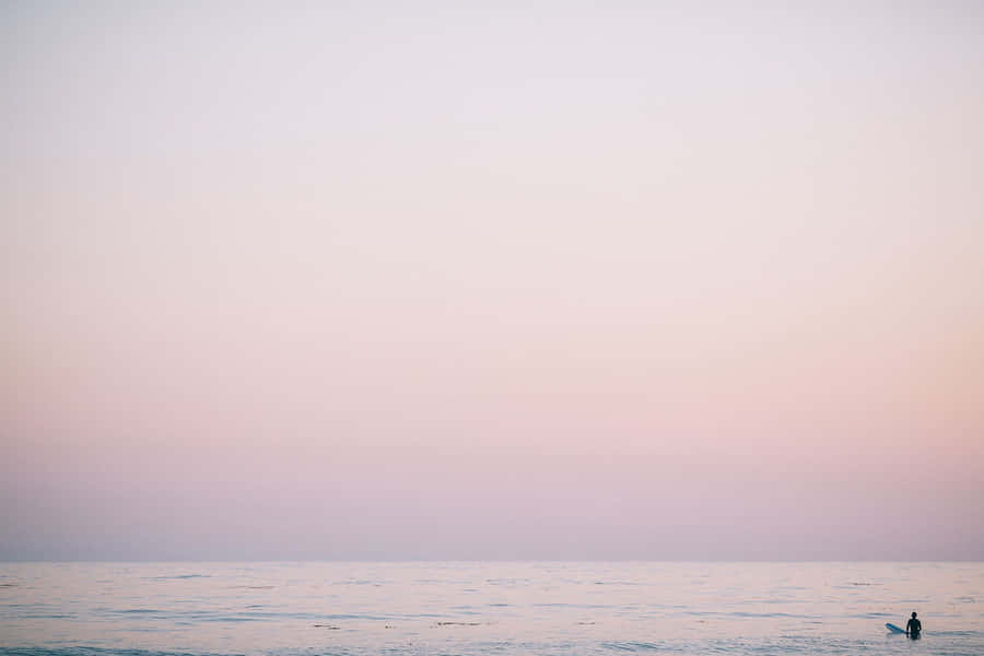 A Person Is Standing On The Beach At Sunset Wallpaper