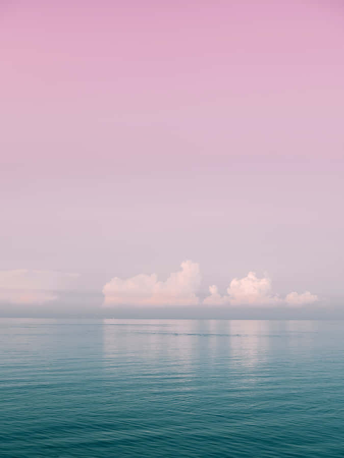 A Pink And Blue Sky With Clouds Over The Ocean Wallpaper