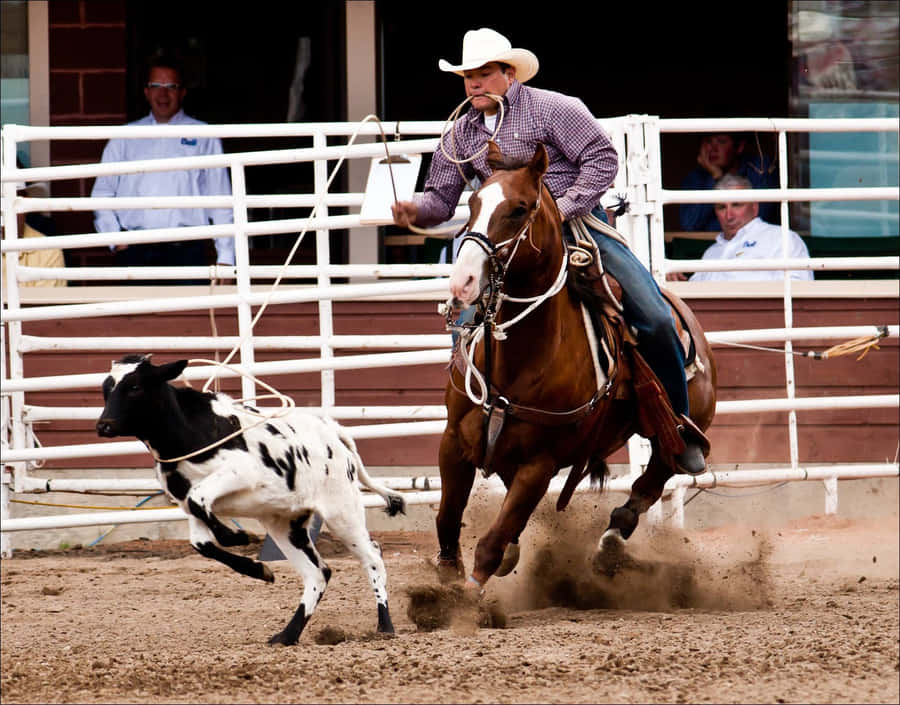 A Rider Clutching Their Cowboy Hat As They Balance On A Bucking Bronco At A Rodeo Wallpaper