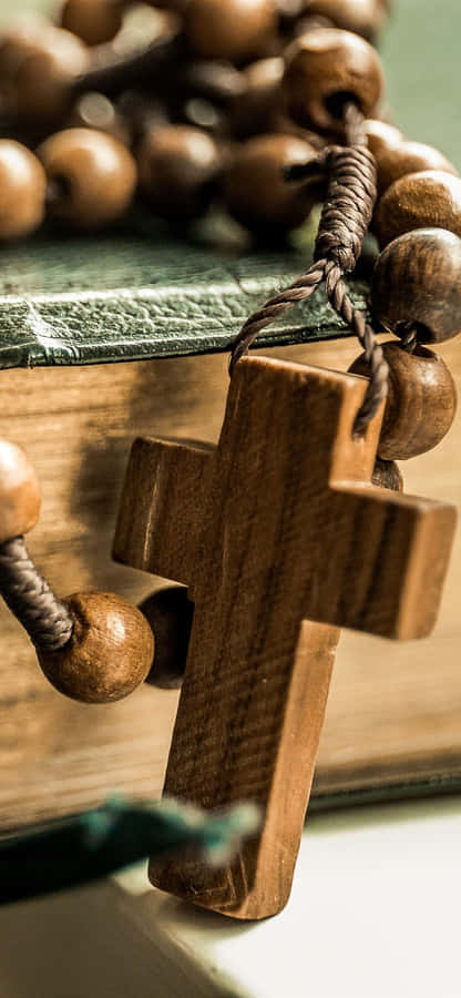 A Wooden Rosary Is Sitting On Top Of A Book Wallpaper