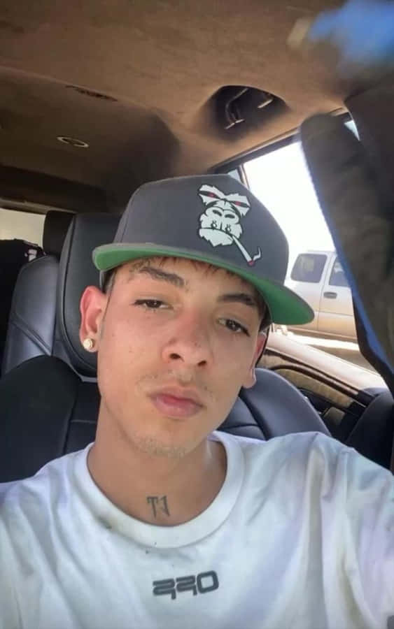 A Young Man In A Hat Is Sitting In A Car Wallpaper