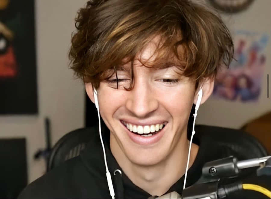 A Young Man Is Smiling While Wearing Headphones Wallpaper