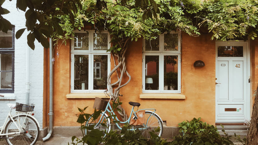 An Orange House With A Lush Green Surrounding Wallpaper
