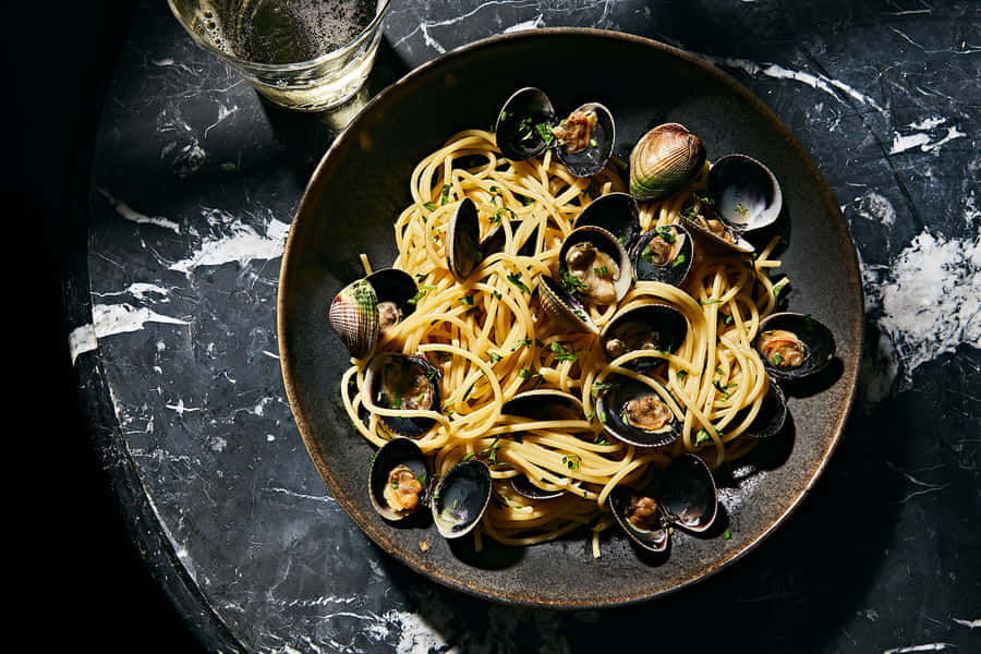 Authentic Italian Spaghetti Alla Vongole Served On A Black Plate Wallpaper
