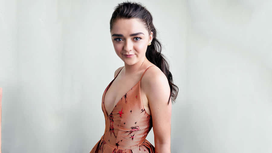 Caption: Maisie Williams Wearing A Formal Dress And Smiling At The Camera During An Event Wallpaper