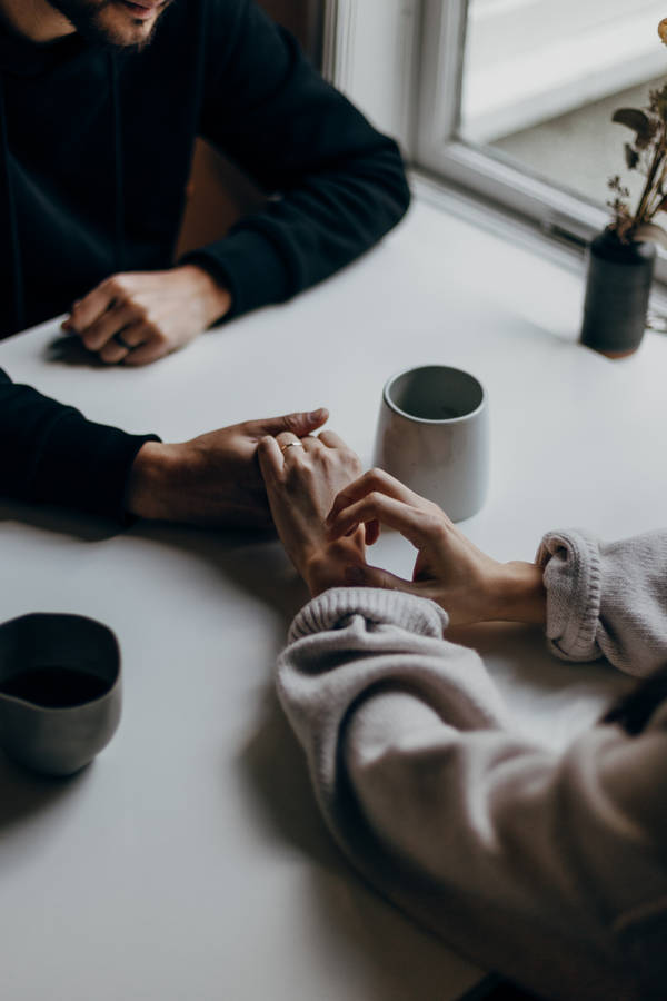 Couple Holding Hands On Table Wallpaper