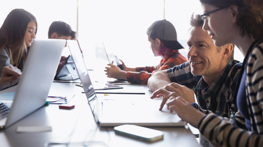 Engaged Learning - Teacher Assisting Student With Laptop Wallpaper