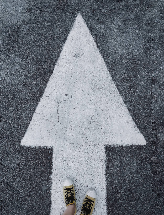 Feet Standing On A White Arrow Wallpaper