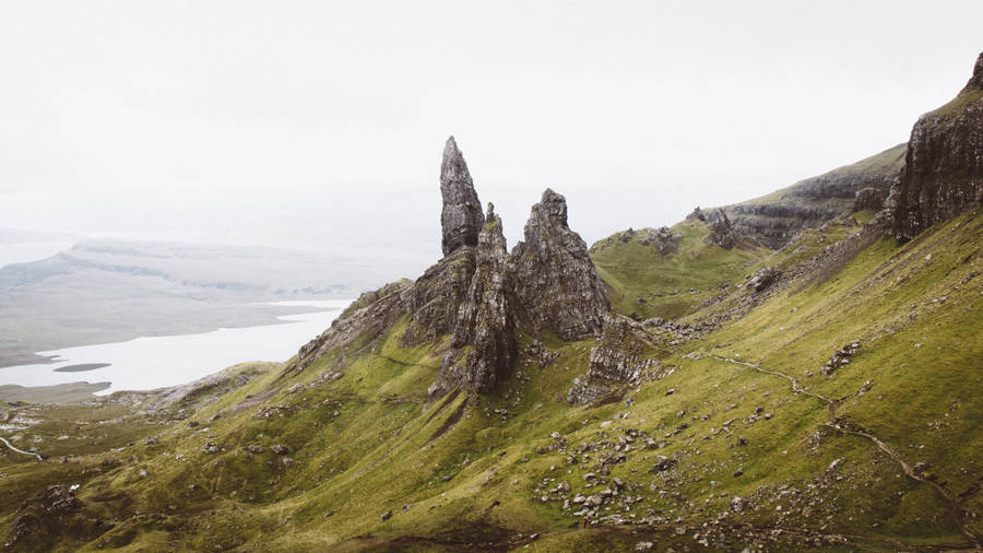 Green And Black Mountain Near Body Of Water Under White And Gray Sky At Daytime Wallpaper