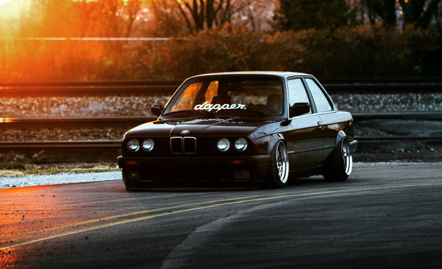 Luxurious Ride: Black Bmw Against A Dramatic Sky Wallpaper