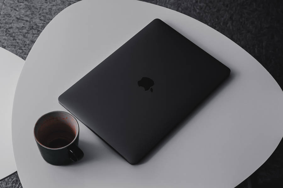 Macbook Pro Beside Mug On Table Wallpaper