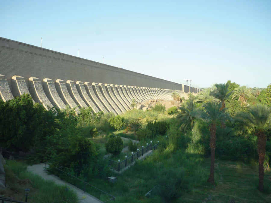 Majestic View Of Aswan High Dam With Green Garden Wallpaper