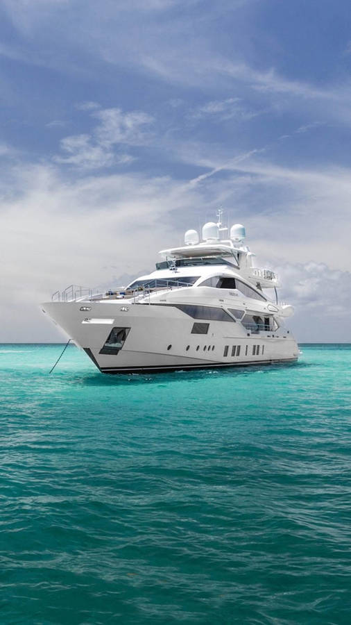 Majestic Yacht Sailing Under A Cloudy Blue Sky Wallpaper