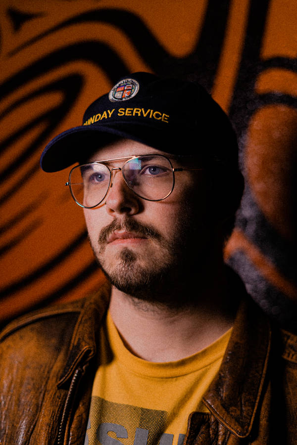 Man In Black Framed Eyeglasses And Black Cap Wallpaper