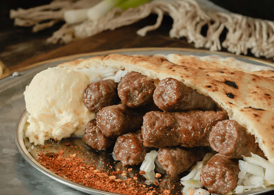 Mouthwatering Grilled Ćevapi Served With Chili Flakes Wallpaper