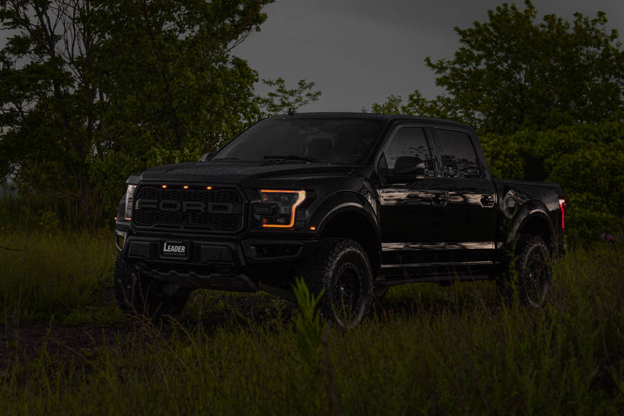 Powerful Ford Raptor With Vibrant Orange Headlights Shining In The Dark Wallpaper